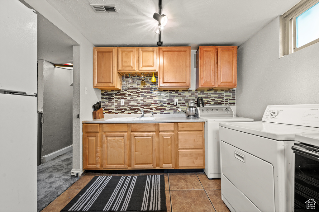 Laundry room featuring light tile flooring, sink, and washing machine and dryer
