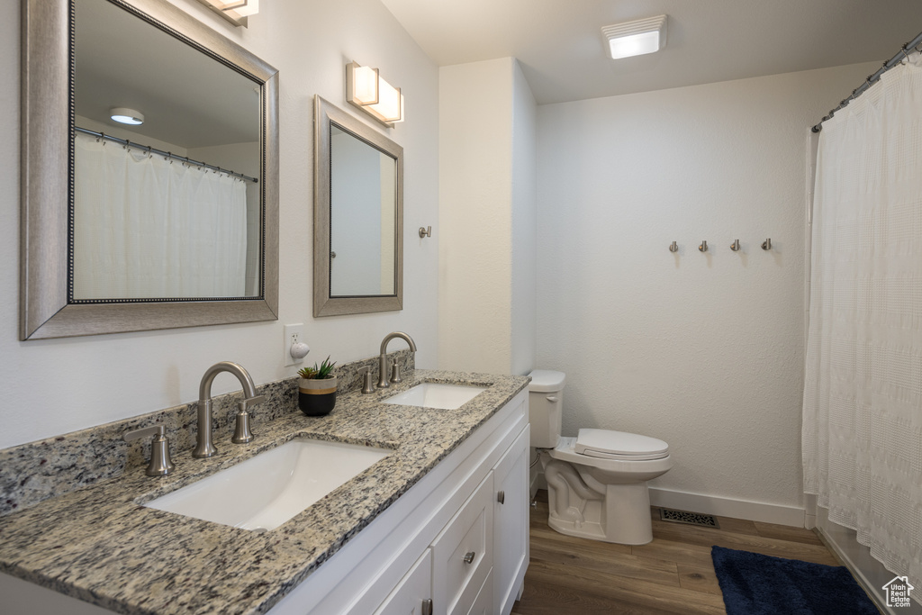 Bathroom featuring toilet, wood-type flooring, and double sink vanity