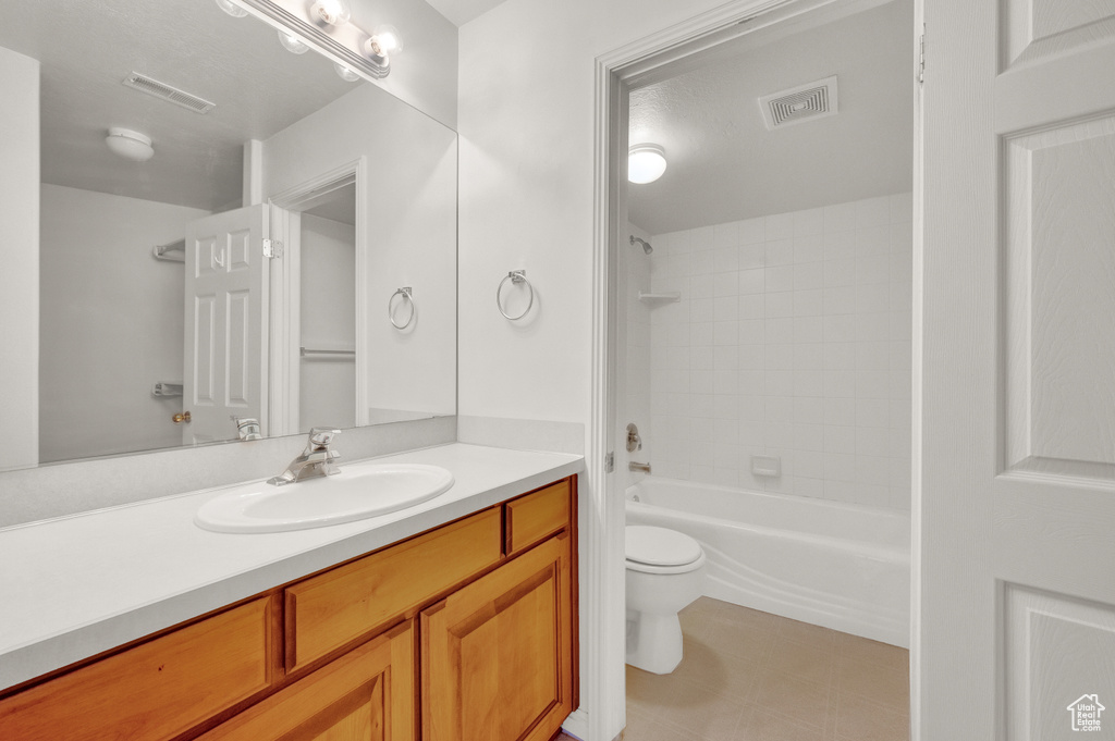 Full bathroom featuring oversized vanity, tiled shower / bath combo, toilet, and tile floors