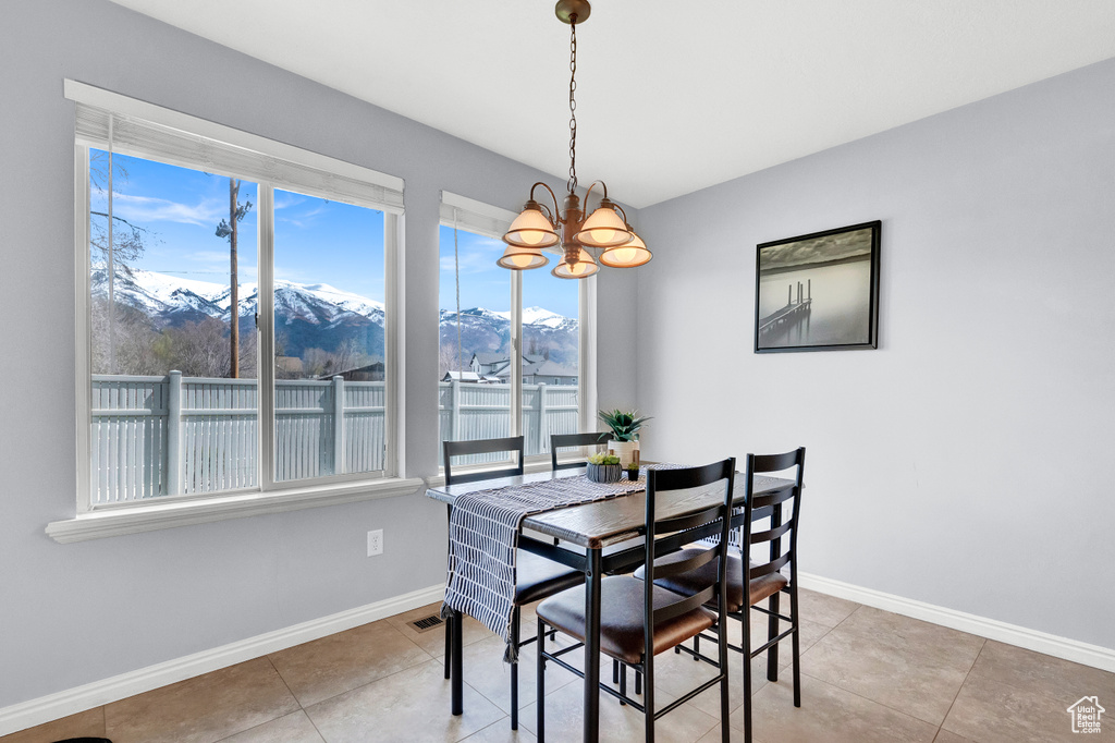 Tiled dining room with a healthy amount of sunlight, a notable chandelier, and a mountain view