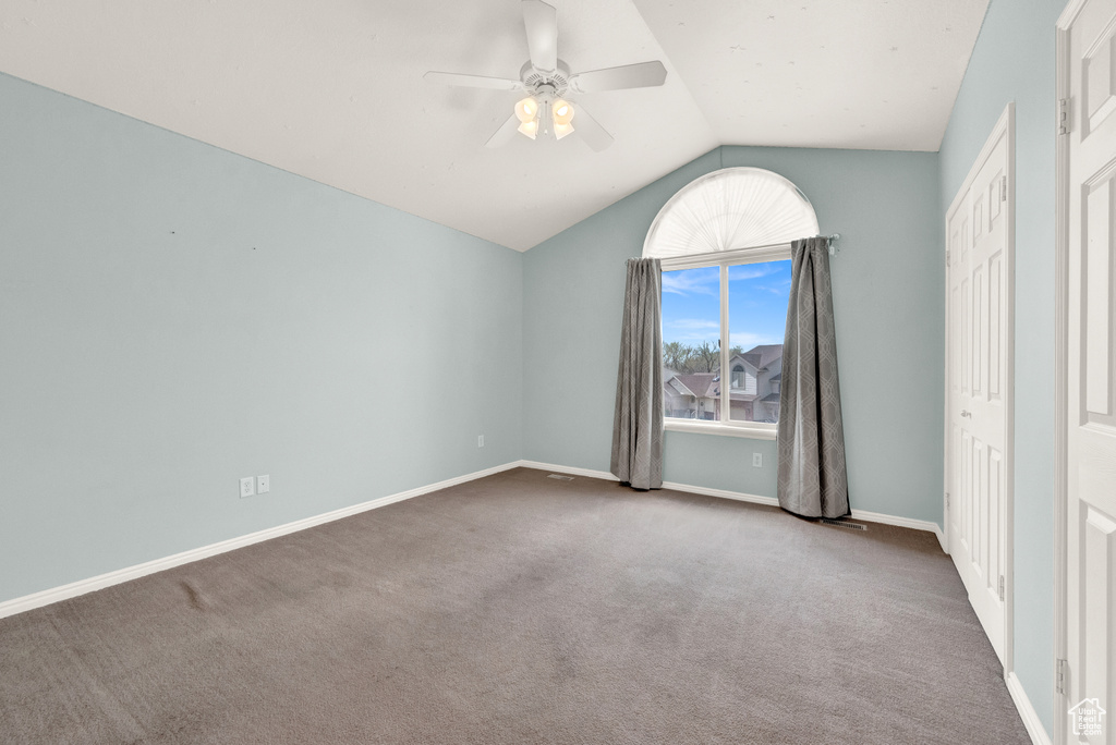 Unfurnished bedroom with lofted ceiling, dark carpet, and ceiling fan