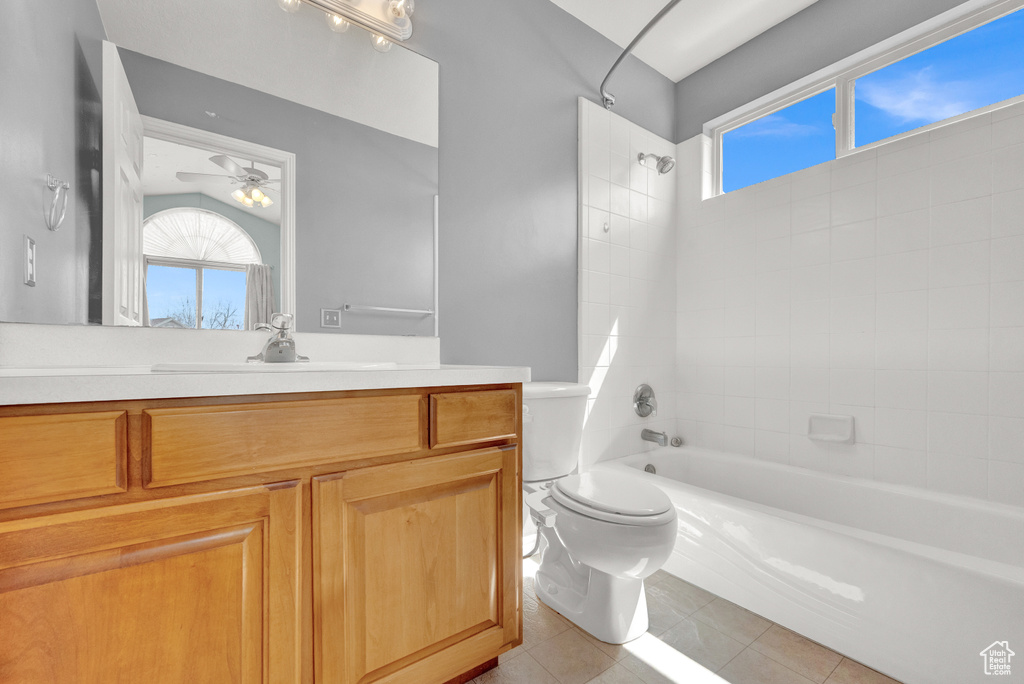Full bathroom with tile floors, tiled shower / bath combo, ceiling fan, toilet, and vanity