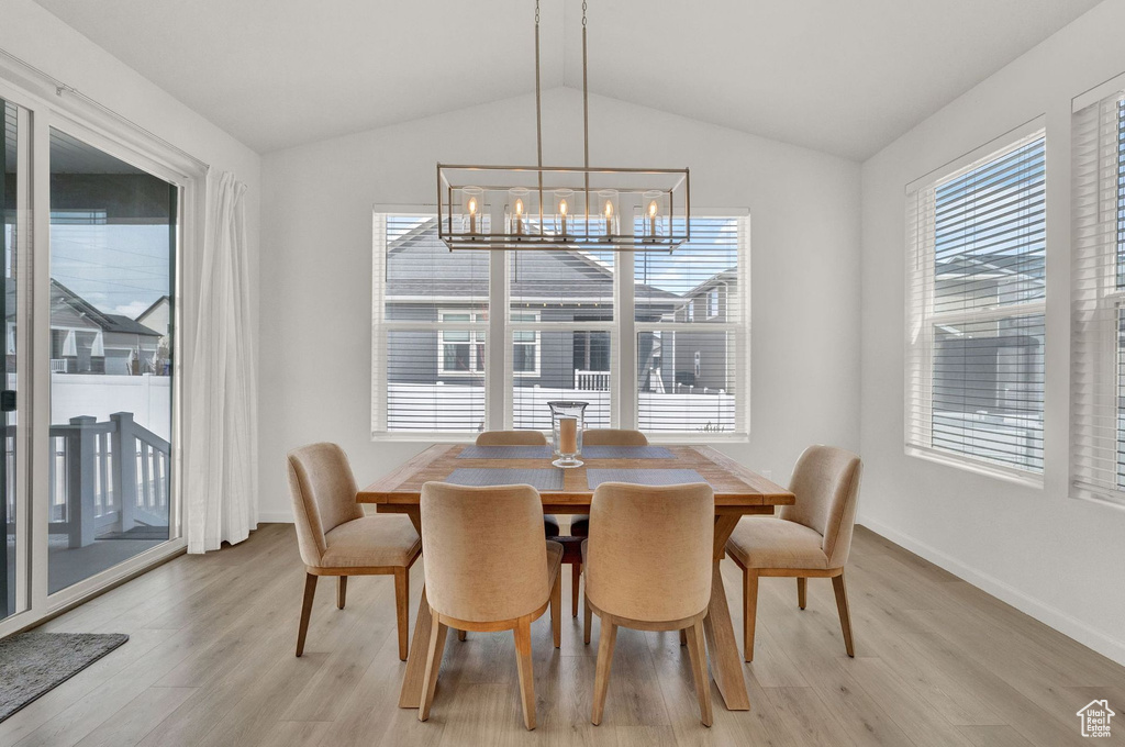 Dining space with an inviting chandelier, vaulted ceiling, and light wood-type flooring