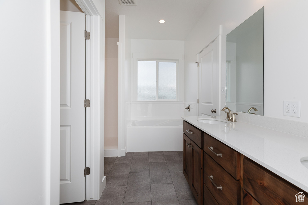 Bathroom featuring a bathtub, tile flooring, and dual bowl vanity