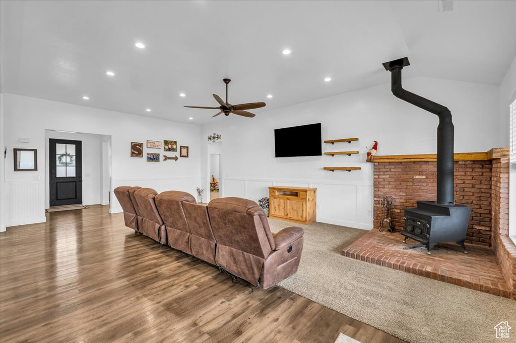 Living room with ceiling fan, a wood stove, and hardwood / wood-style flooring