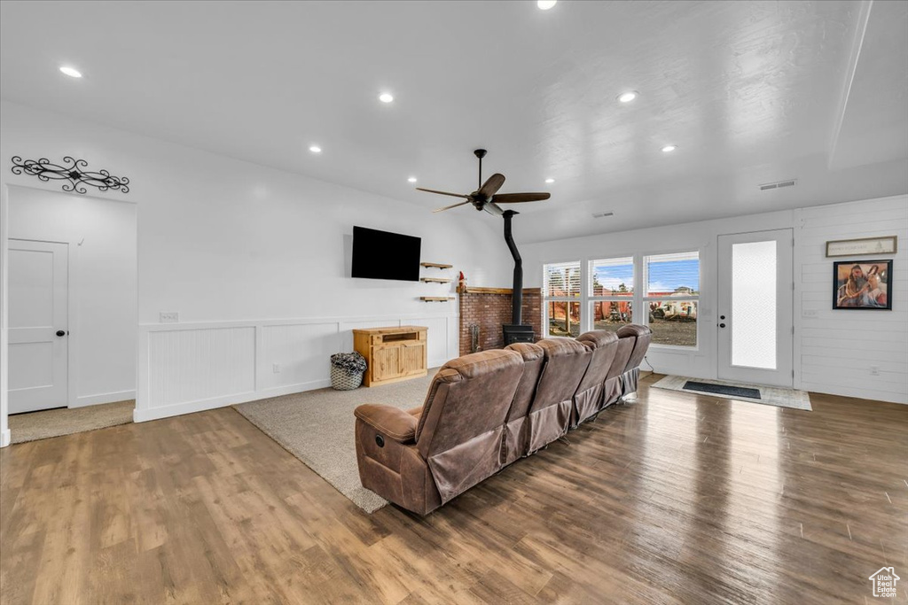 Living room featuring dark hardwood / wood-style flooring, ceiling fan, and a wood stove