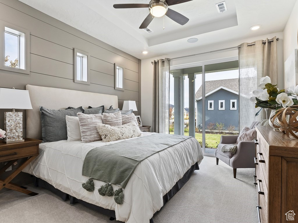 Bedroom with ceiling fan, access to exterior, light carpet, and a tray ceiling