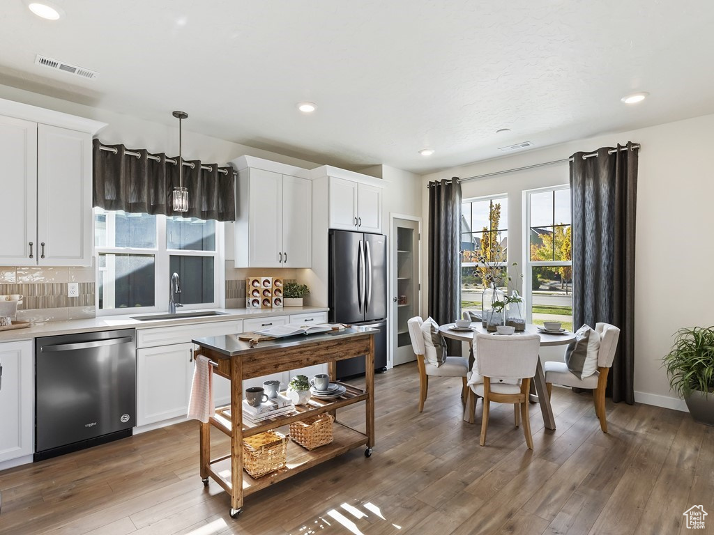 Kitchen with dark hardwood / wood-style flooring, sink, stainless steel appliances, and white cabinetry
