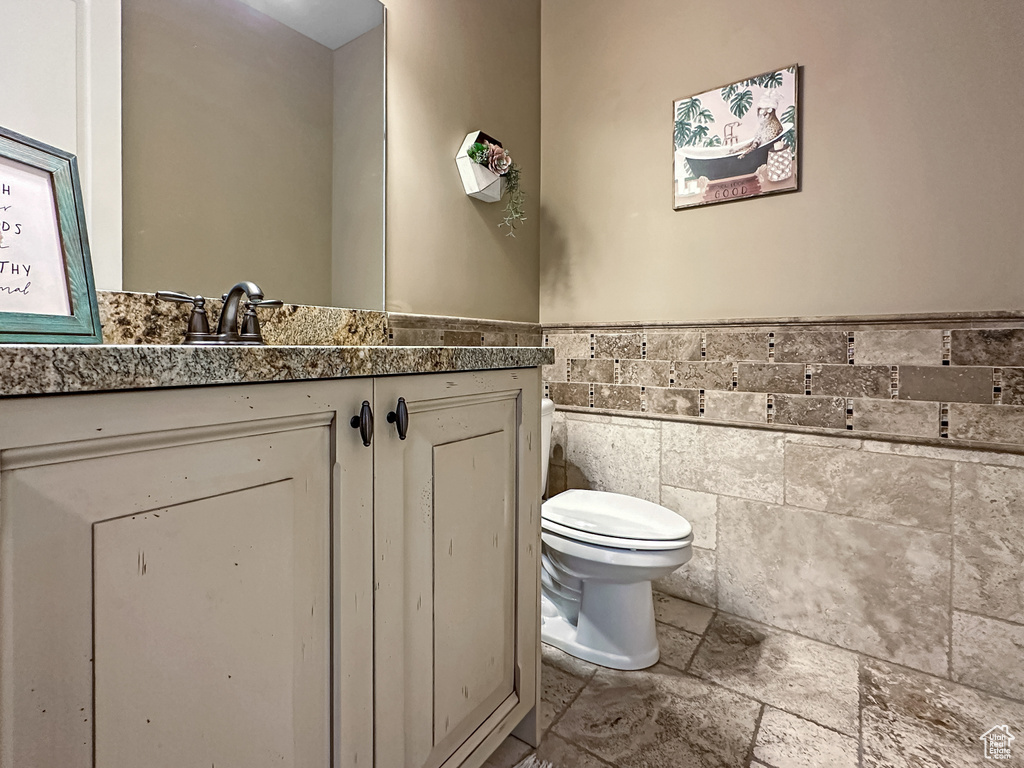 Bathroom featuring toilet, tile walls, tile flooring, and vanity