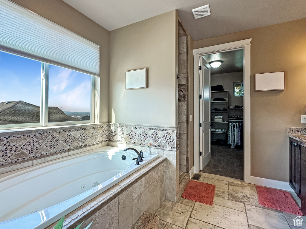 Bathroom featuring tiled bath, tile flooring, and vanity