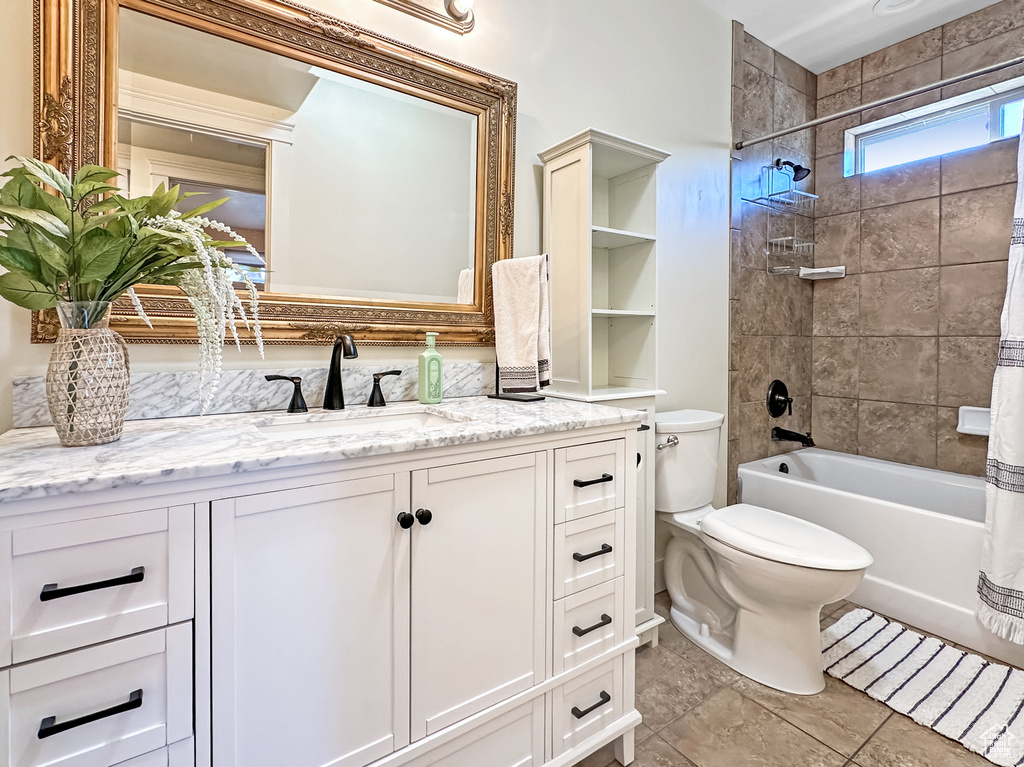 Full bathroom featuring toilet, tile floors, tiled shower / bath combo, and vanity