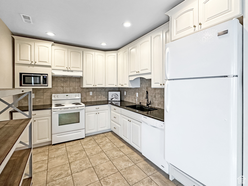 Kitchen with white cabinetry, white appliances, light tile flooring, and sink
