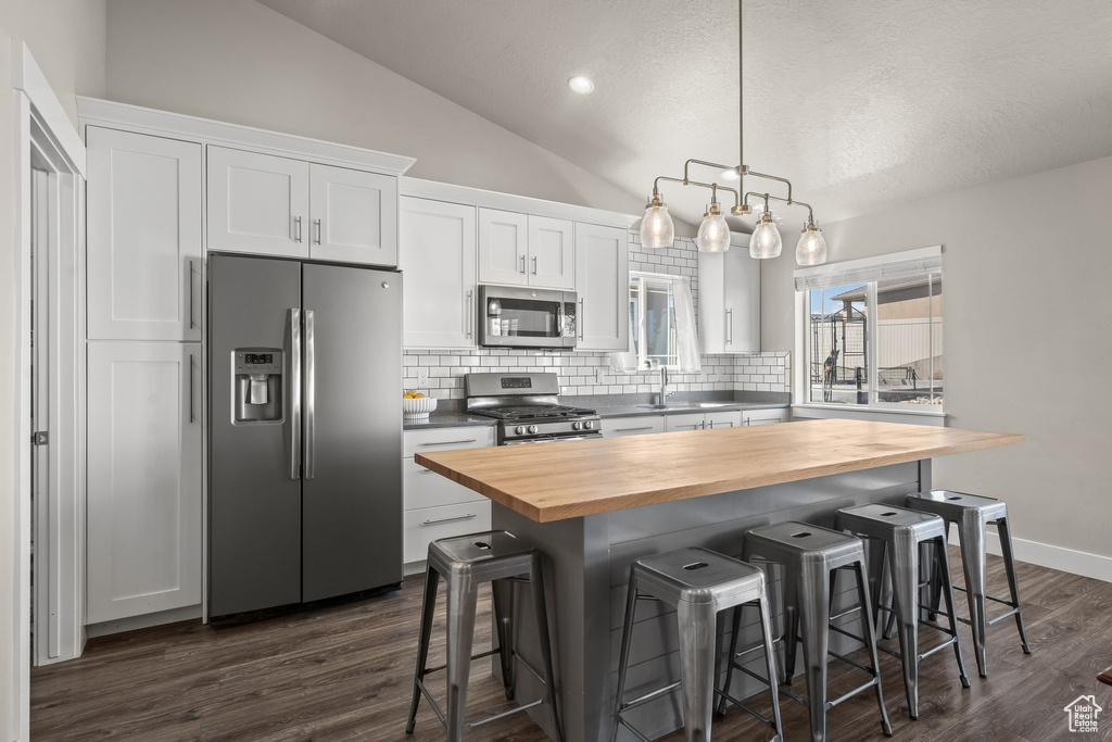 Kitchen featuring stainless steel appliances, white cabinets, dark hardwood / wood-style flooring, decorative light fixtures, and butcher block countertops