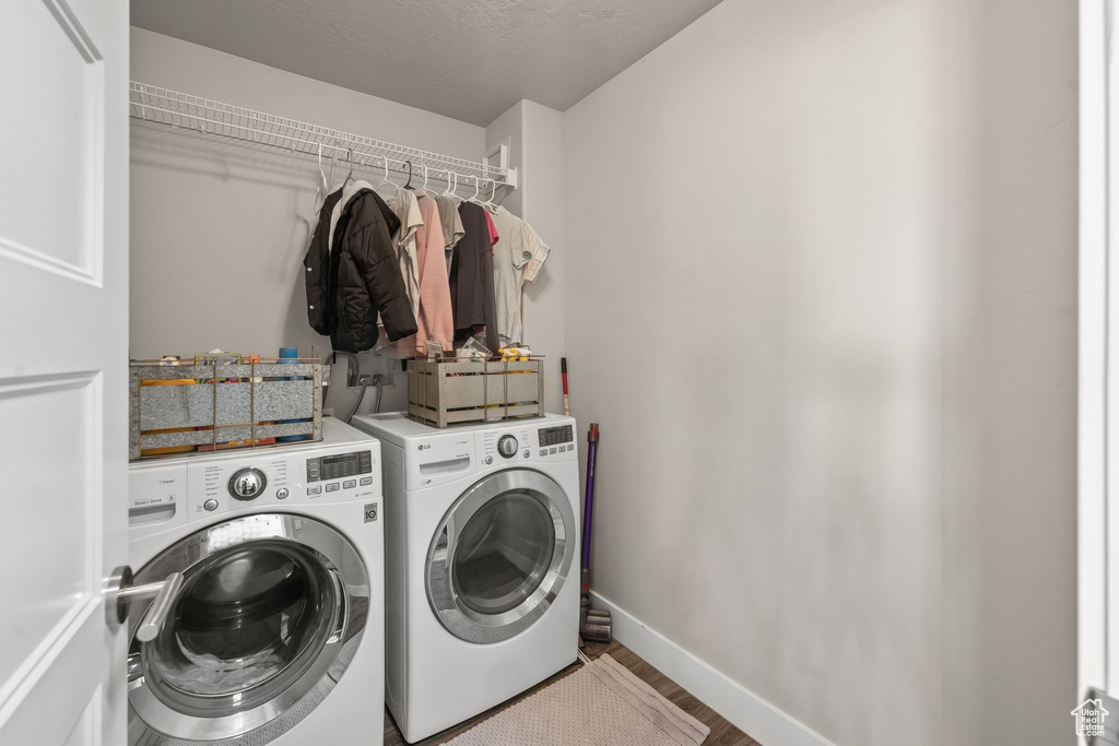 Clothes washing area featuring washing machine and clothes dryer and hardwood / wood-style floors