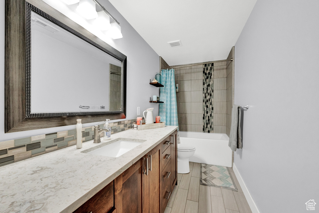 Full bathroom with shower / bathtub combination with curtain, tile floors, backsplash, toilet, and vanity
