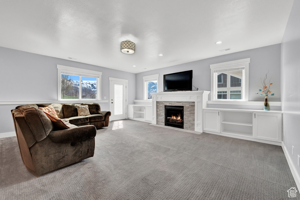 Living room featuring light carpet and a stone fireplace