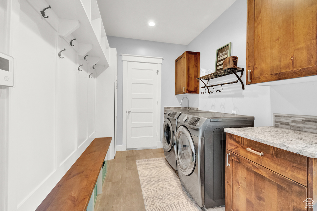 Washroom featuring light hardwood / wood-style floors, cabinets, and independent washer and dryer