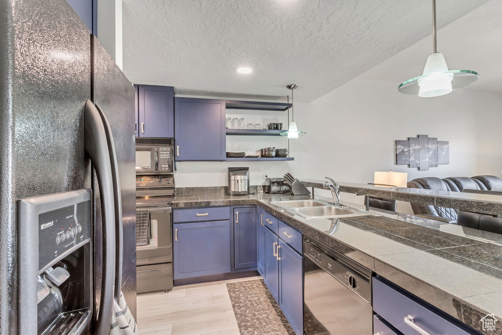 Kitchen featuring sink, hanging light fixtures, blue cabinetry, black appliances, and light wood-type flooring