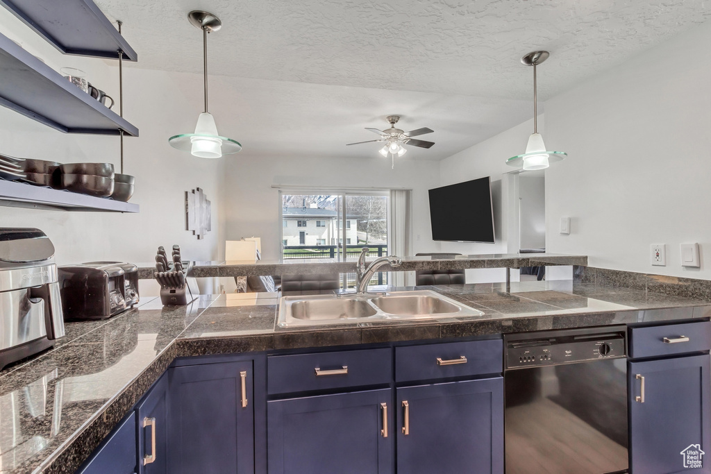Kitchen with hanging light fixtures, ceiling fan, sink, blue cabinetry, and dishwasher
