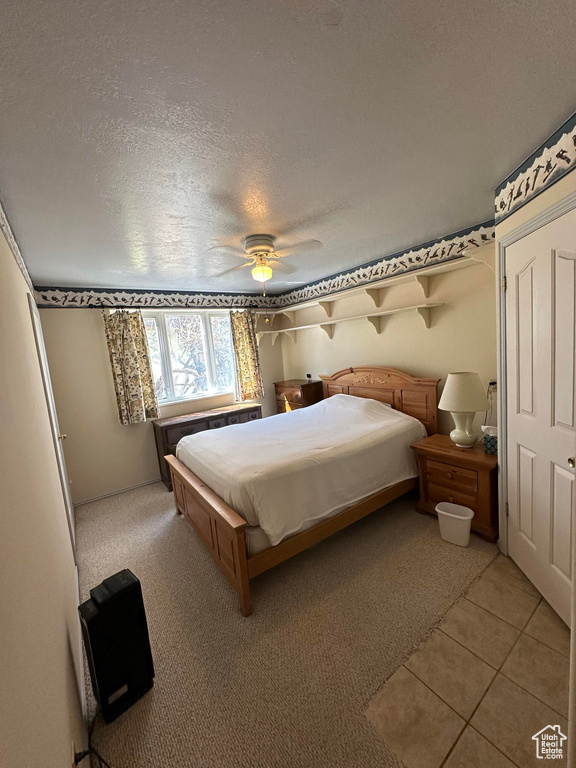 Tiled bedroom with ceiling fan and a textured ceiling