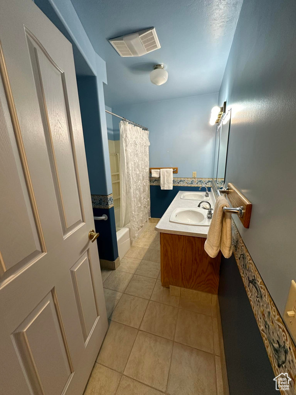 Bathroom with shower / bath combo with shower curtain, tile floors, and vanity