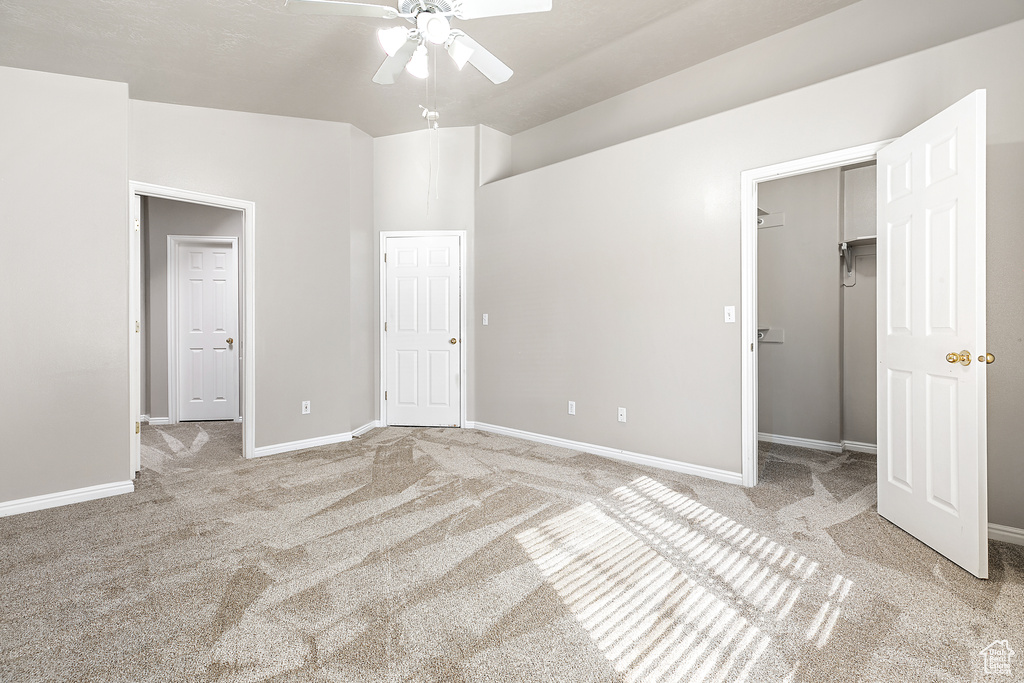 Empty room with vaulted ceiling, light colored carpet, and ceiling fan