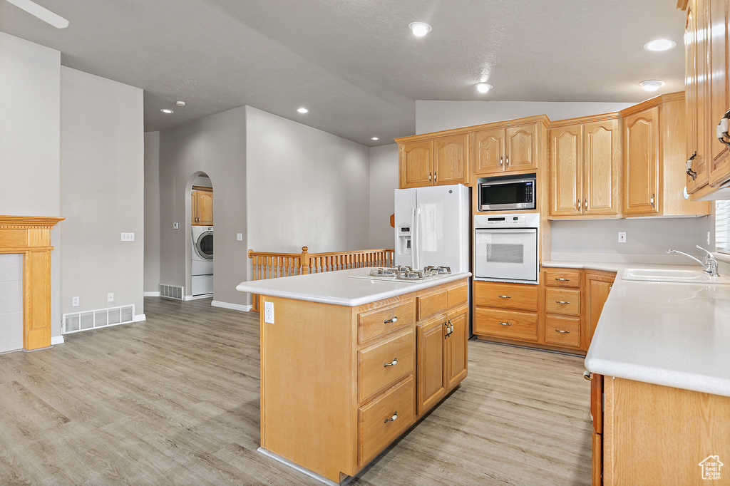 Kitchen with a kitchen island, white appliances, sink, and light wood-type flooring