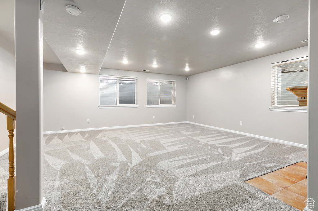 Empty room featuring a textured ceiling and light colored carpet
