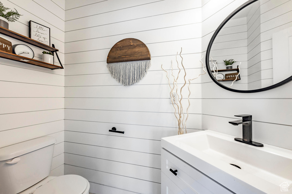 Bathroom featuring wooden walls, toilet, and large vanity