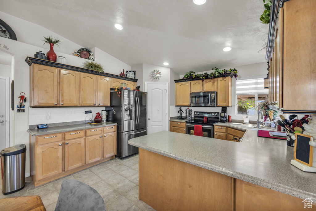 Kitchen with appliances with stainless steel finishes, lofted ceiling, backsplash, light tile floors, and sink