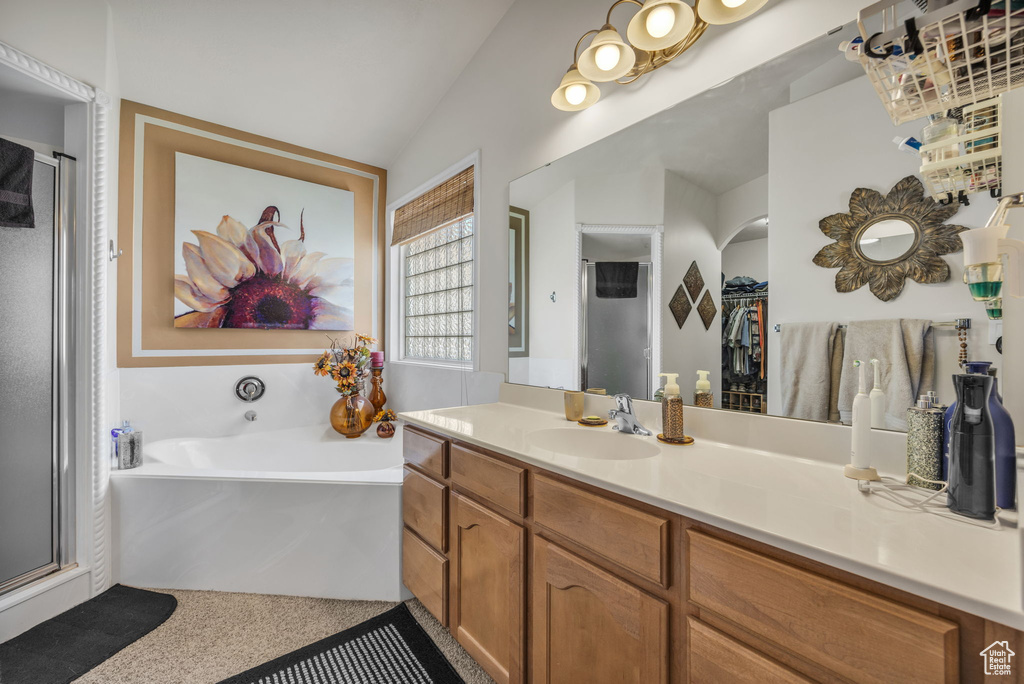 Bathroom featuring vanity, vaulted ceiling, and separate shower and tub