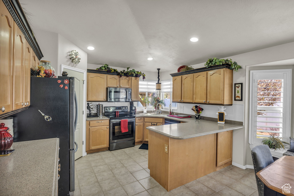 Kitchen featuring light tile flooring, decorative light fixtures, electric range, and kitchen peninsula