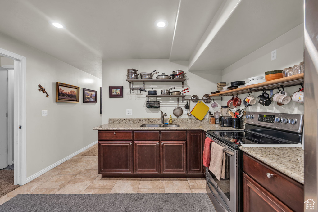 Kitchen with light tile flooring, light stone countertops, stainless steel electric range oven, and sink