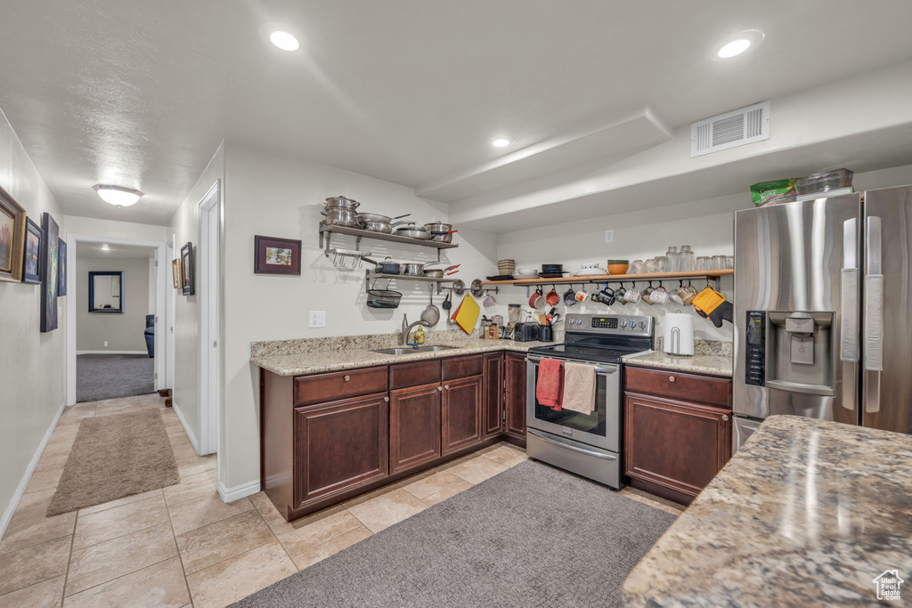Kitchen featuring sink, light stone counters, light tile flooring, and stainless steel appliances