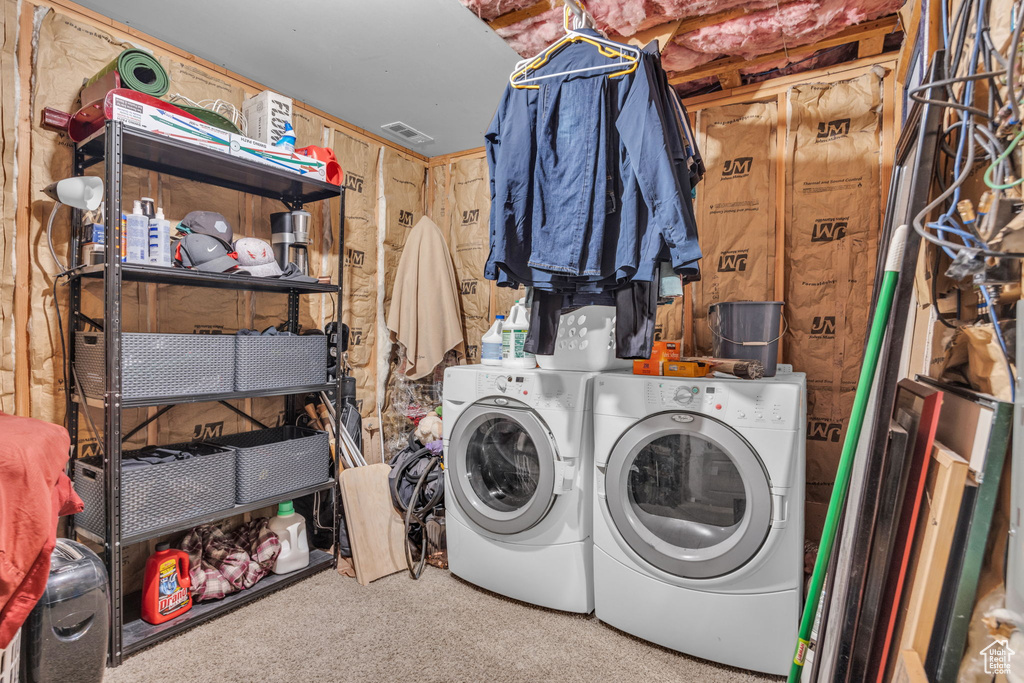 Clothes washing area featuring wooden walls, washer and clothes dryer, and light carpet