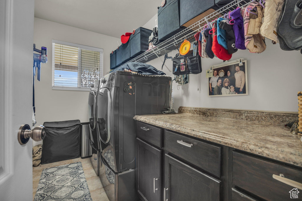 Laundry room featuring light tile floors, cabinets, and washer and dryer