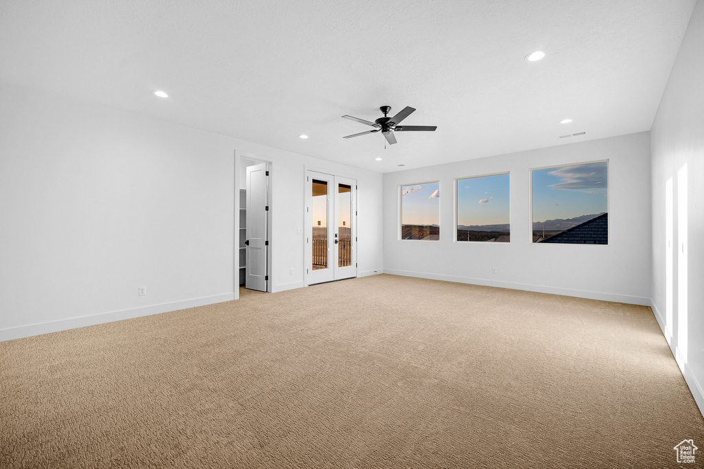 Unfurnished room featuring ceiling fan, light carpet, and french doors