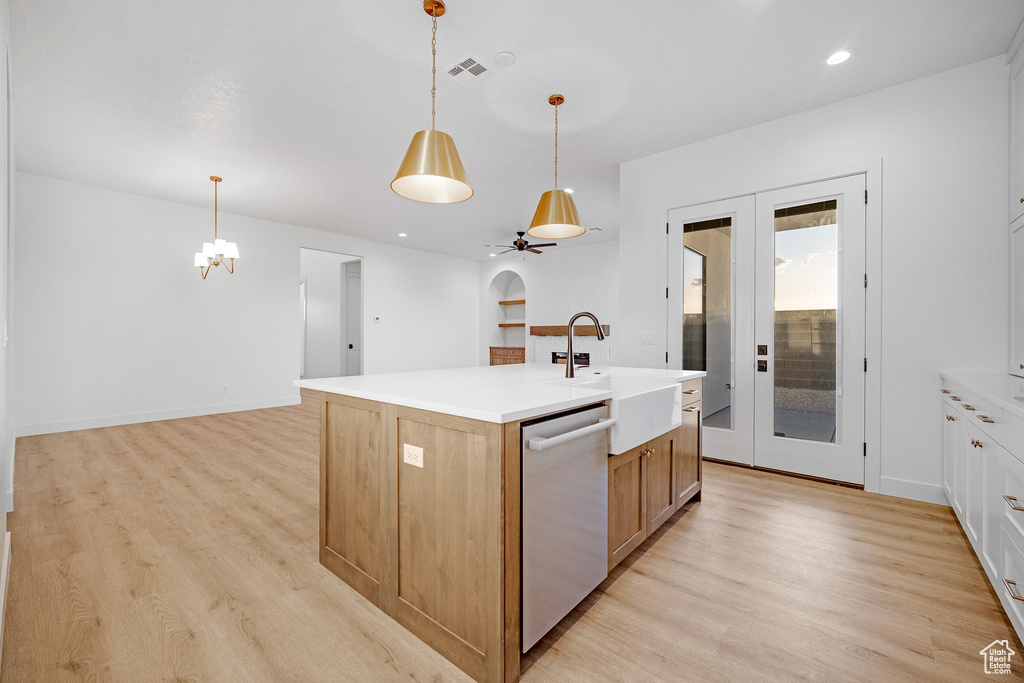 Kitchen featuring hanging light fixtures, sink, an island with sink, light hardwood / wood-style flooring, and dishwasher