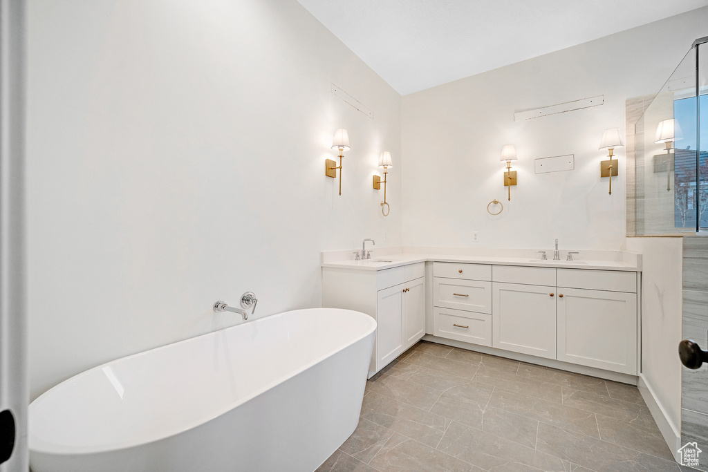 Bathroom featuring a bathing tub, dual sinks, tile flooring, and large vanity