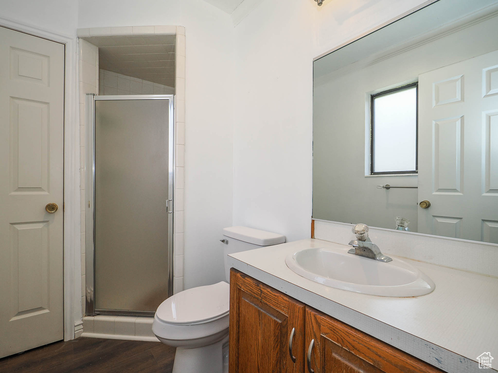 Bathroom featuring hardwood / wood-style flooring, a shower with door, toilet, and vanity