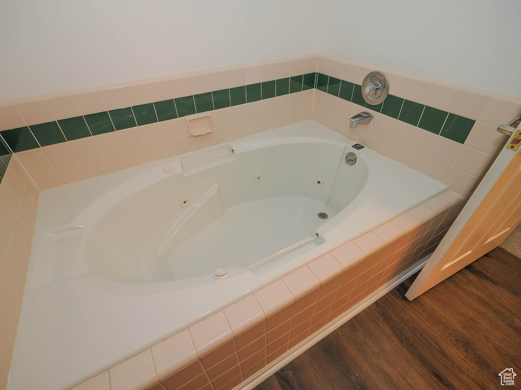 Bathroom featuring tiled tub and hardwood / wood-style floors