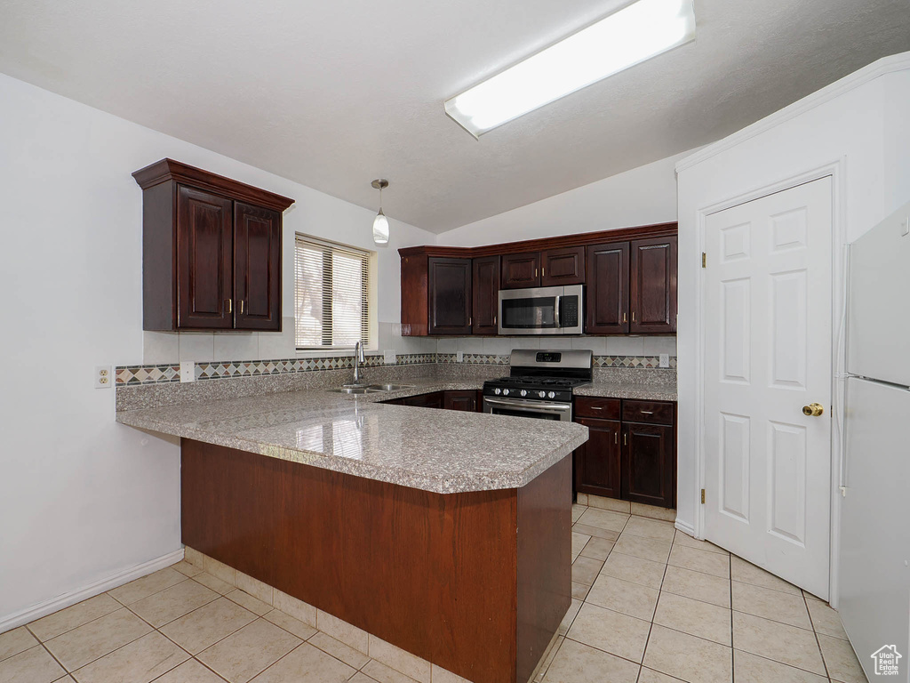 Kitchen featuring light tile flooring, kitchen peninsula, stainless steel appliances, vaulted ceiling, and sink