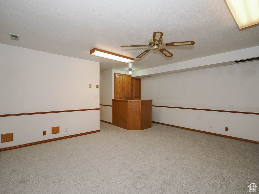 Unfurnished room featuring light colored carpet, ceiling fan, and a textured ceiling