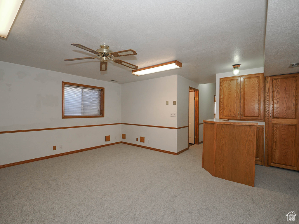 Empty room with light carpet, ceiling fan, and a textured ceiling