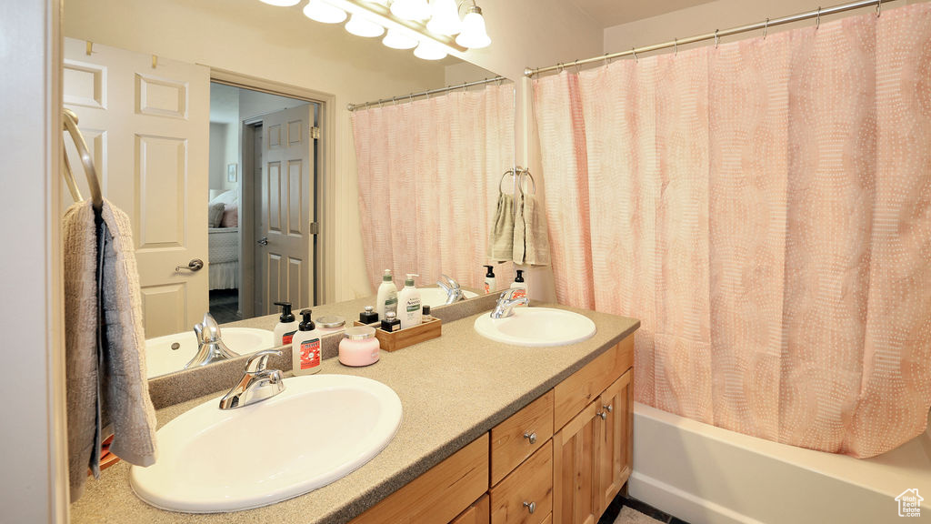 Bathroom with double sink vanity and shower / tub combo with curtain