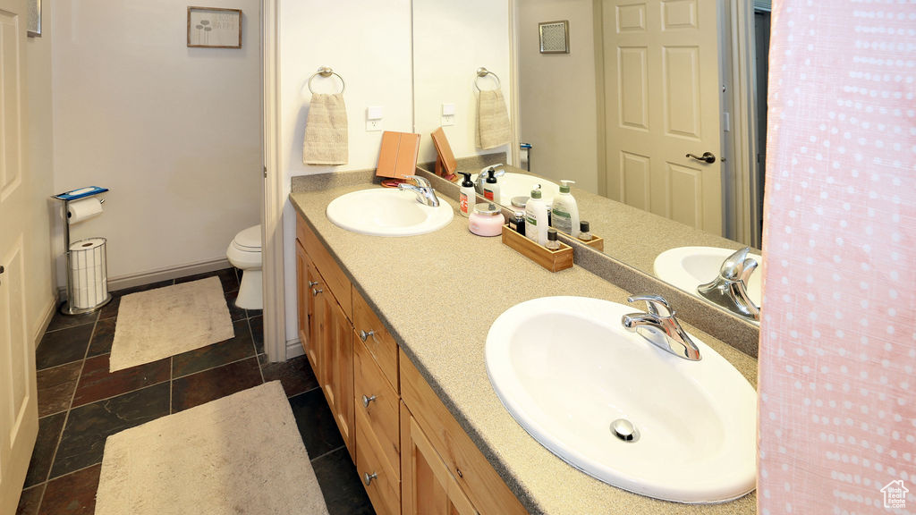 Bathroom featuring tile flooring, toilet, and dual vanity