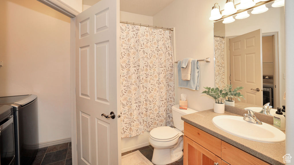 Bathroom with independent washer and dryer, tile flooring, toilet, and vanity
