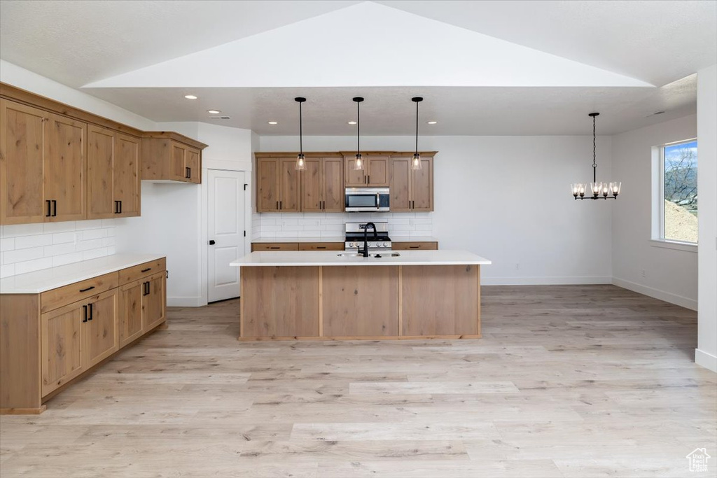 Kitchen with a chandelier, backsplash, appliances with stainless steel finishes, and light wood-type flooring