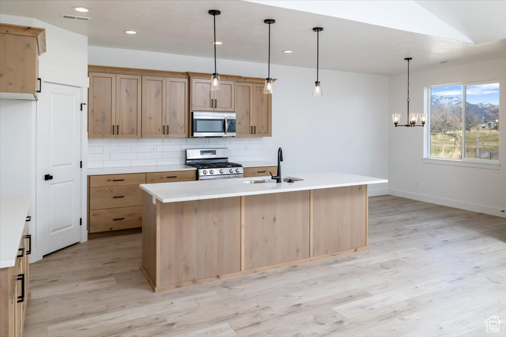 Kitchen with pendant lighting, sink, stainless steel appliances, and light wood-type flooring