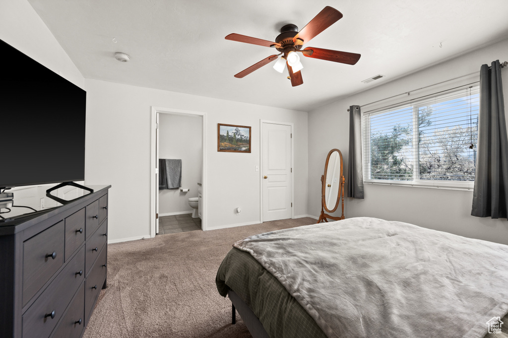 Carpeted bedroom with ensuite bath and ceiling fan